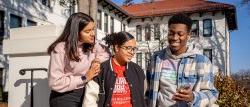 One student holding a cell phone, showing two students the screen