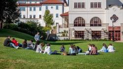 students attending class outside, sitting on lawn