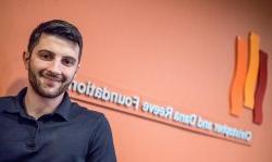 A student standing in front of a sign at his internship.