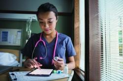 Nurse using digital tablet in hospital room