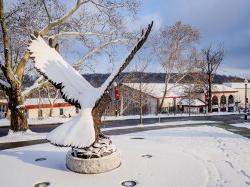 Hawk statue covered in snow on a sunny day