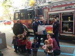 Young children posing with Little Falls Fire Fighters and fire truck