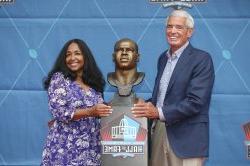 Melanie Mills and Jim Mora Sr. stand next to Sam Mills' head bust