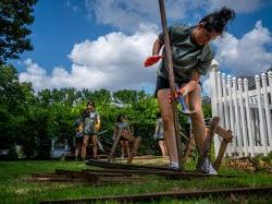 Student volunteer breaking apart scrap wood