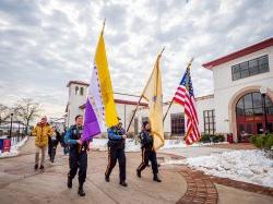 Three flags are carried by police officers in the procession celebrating Women’s History Month.