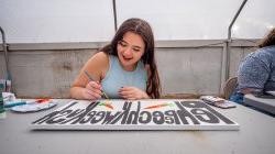 Female student paints sign.