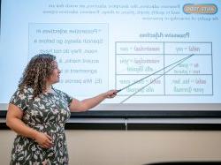 A woman points to a screen with Spanish adjectives on it.