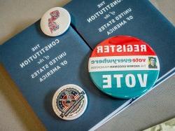 Sm所有 booklets of The Constitution of the United States of America 和 buttons encouraging people to vote.