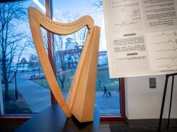 A harp against a window with a view of campus behind it.