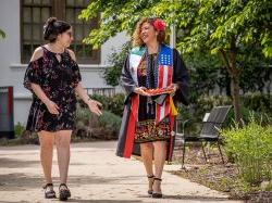 A graduate and her college-age daughter walk on campus.