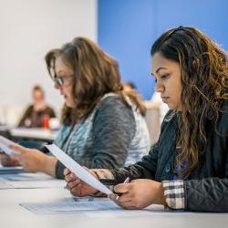 Nursing students in class reading papers.