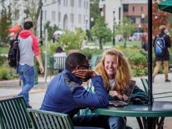 Two students sitting outside of Cafe Diem looking at something on a laptop.