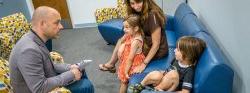 Image of a clinician talking with a parent and two children in a clinical setting.