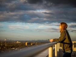 Student gazing out at view of manhattan skyline from campus building.